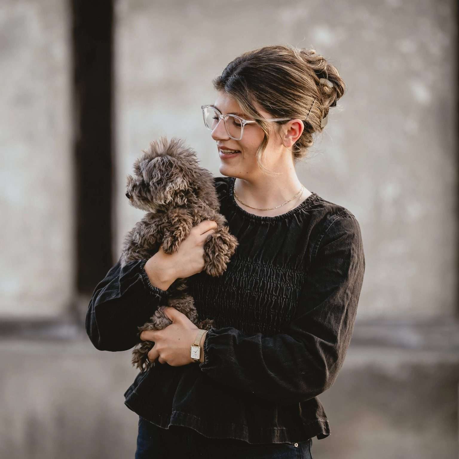 Foto von Corinne. Sie hält ihre Hündin Lilly im Arm. Ein brauner kleiner Pudel.